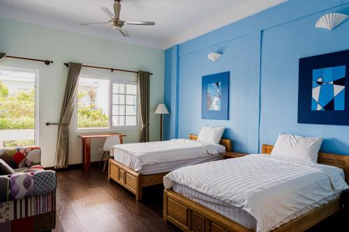two beds in a room with blue walls at Ananas Beach Hotel in Vung Tau