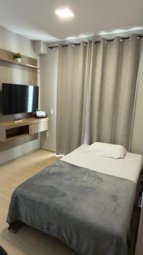a bedroom with a bed and a flat screen tv at Ap Mirante Fortaleza 5min da Praia com Piscina e Rooftop para 6 pessoas in Fortaleza