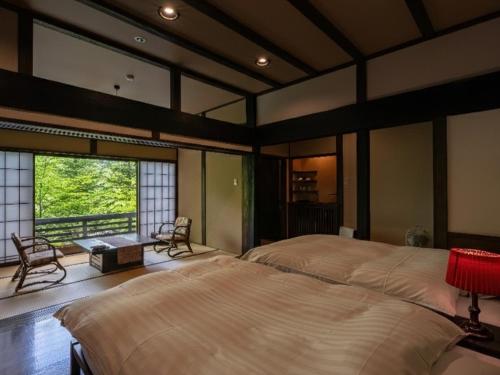 a bedroom with two beds and a large window at Konashi No Yu Sasaya in Matsumoto