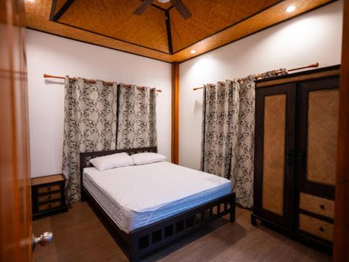 a bedroom with a bed and a ceiling at บ้านกูรูรีสอร์ท in Ban Thung Satong