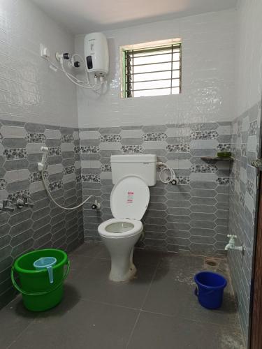 a bathroom with a toilet and a green bucket at Sheshatara Homestay in Honāvar