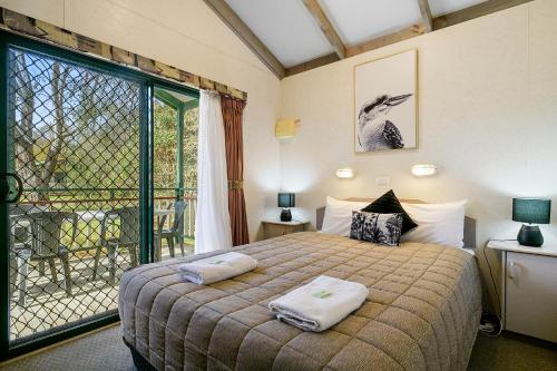 a bedroom with a bed and a large window at Howlong Caravan Park in Howlong