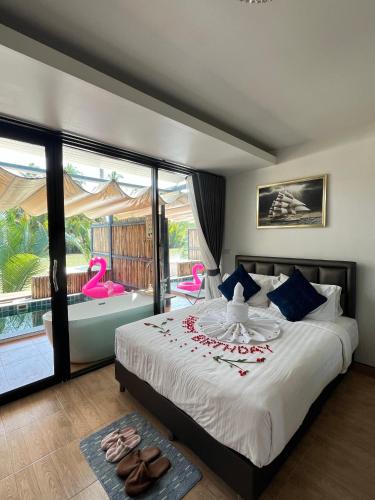 a bedroom with a bed and a balcony with pink chairs at Phetra pool villas in Suratthani