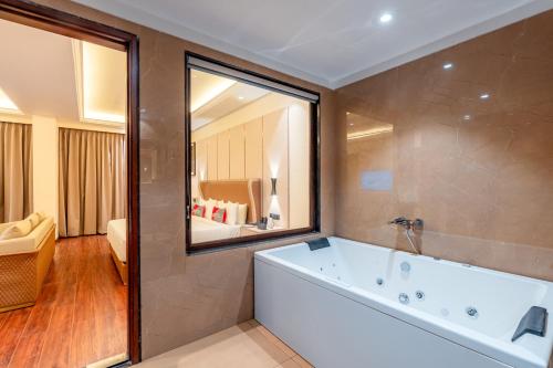 a bathroom with a tub and a large mirror at Playotel Premier, Ujjain in Ujjain