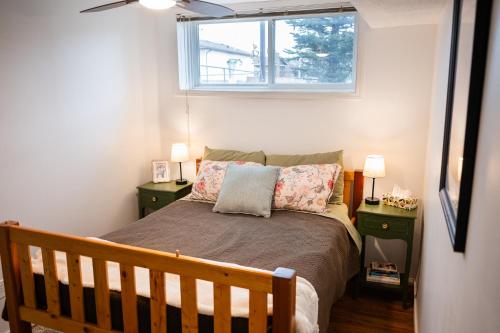 a bedroom with a bed with two night stands and a window at Spacious 2-Bedroom Basement Suite in Whitehorn, Close to Calgary Airport, Hospital, & Train in Calgary
