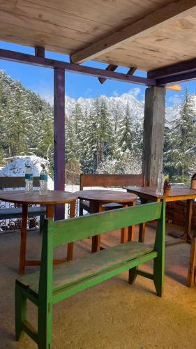 Eine grüne Bank steht unter einem Tisch, im Hintergrund sind Berge zu sehen. in der Unterkunft DADU'S Cafe in Sainj