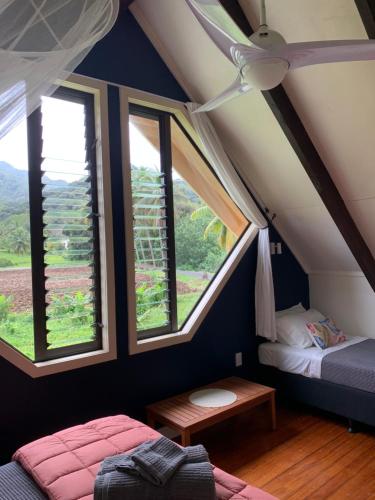 a bedroom with two beds and windows in a attic at Sea Turtle Lodge and Villas in Rarotonga