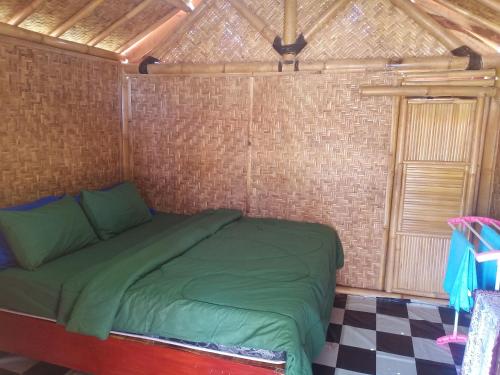 a bedroom with a green bed in a brick wall at Linkgreen Homestay Lombok in Tetebatu