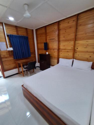 a bedroom with a large bed with wooden walls at Beach cabin uppuveli in Trincomalee