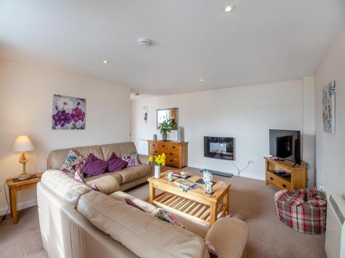 a living room with a couch and a tv at Bwthyn Hudol - Uk46711 in Pwllheli