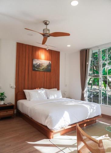 a bedroom with a large bed with a ceiling fan at Nuearnaam Lychee House Chiang Mai in Ban Pa Miang