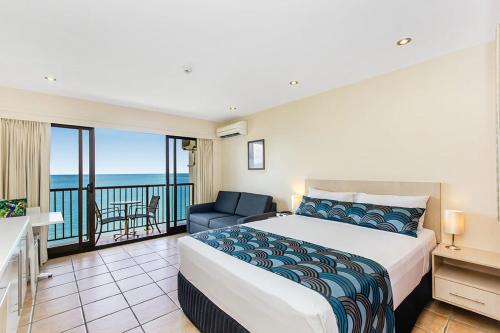 a bedroom with a bed and a balcony with the ocean at Aquarius On The Beach in Townsville