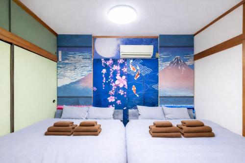 two beds in a room with a mural at 1200IN&OUT 4people 35m2 2Queenbed! 1sofabed! Exclusive house Shinjuku 18 minutes Shibuya 22 minutesIkebukuro 11 minutes in Tokyo