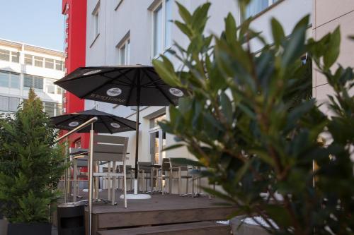 una fila di tavoli e sedie con ombrelloni di Goethe Hotel Messe by Trip Inn a Francoforte sul Meno