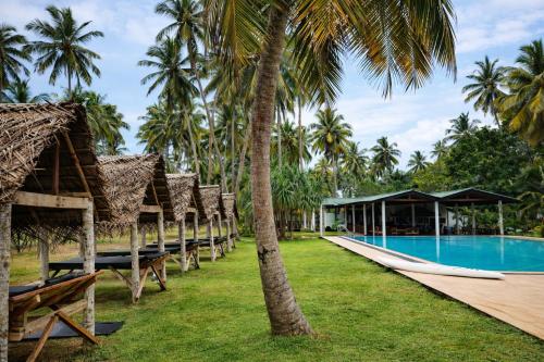 a resort with a swimming pool and palm trees at Helios Beach Resort in Tangalle