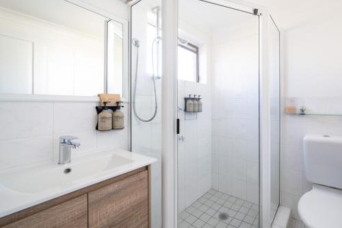 a white bathroom with a shower and a sink at Ben Chifley Motor Inn in Bathurst