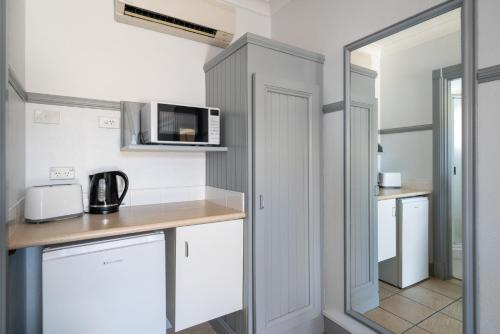 a kitchen with white cabinets and a microwave at Ben Chifley Motor Inn in Bathurst