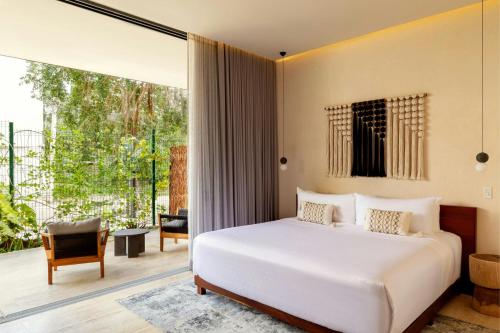 a bedroom with a bed and a large window at Bloom Tulum, Apartments by Marriott Bonvoy in Tulum