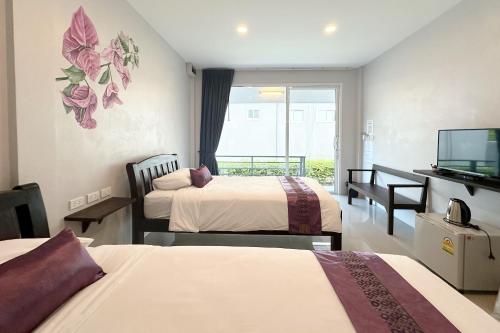 a hotel room with two beds and a flat screen tv at Be Leaf Resort SHA in Thalang