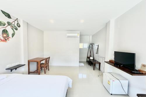 a bedroom with a bed and a desk and a television at Be Leaf Resort SHA in Thalang