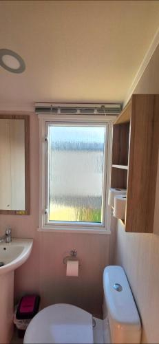 a bathroom with a toilet and a sink and a window at Mason's Morecambe Memories in Heysham