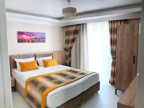 a bedroom with a bed with yellow pillows and a window at Alfa Apart Hotel in Antalya