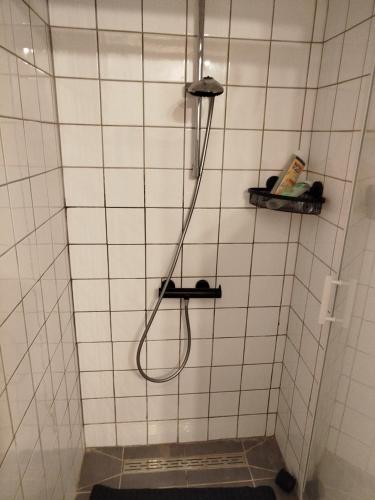 a shower with a hose in a white tiled bathroom at Appartement Neuf Raismes in Raismes