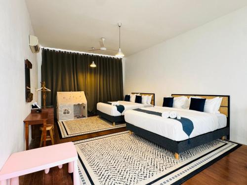 a bedroom with two beds and a desk and a table at Courtyard by Heritage Row in George Town