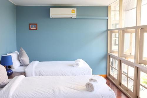 a room with two beds and a blue wall at Baan Ongkharak bed & breakfast in Bangkok