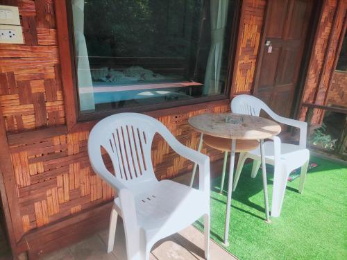 two chairs and a table on the porch of a cabin at saithai forest homstay in Krabi