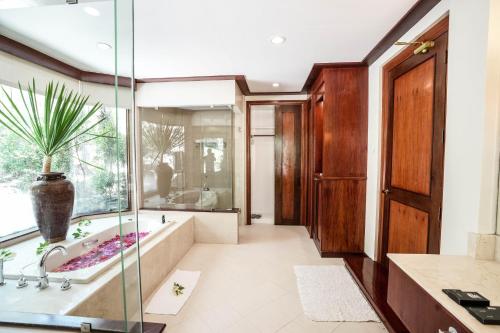 a bathroom with a tub and a glass shower at El Mar Resort in Sampong