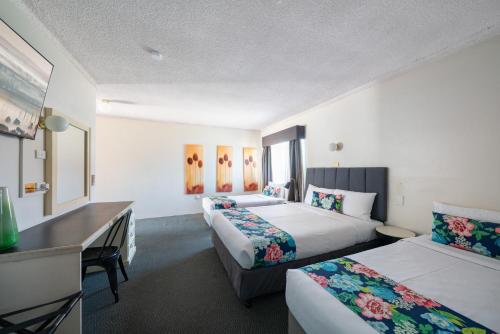 a hotel room with two beds and a desk at Ben Chifley Motor Inn in Bathurst