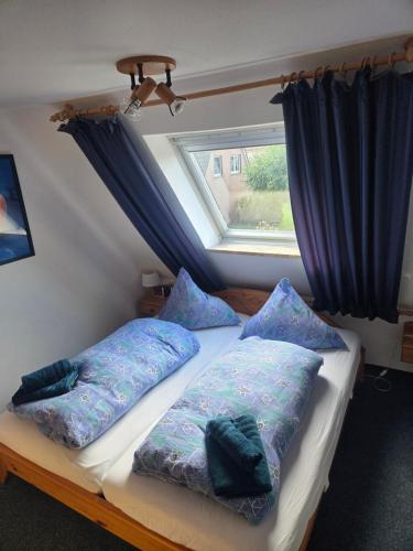 a bedroom with a bed with pillows and a window at up ` Achterdeck in Dornum