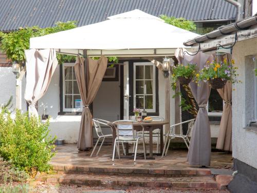 a table and chairs under an umbrella on a patio at Little Millhayes in Thorverton