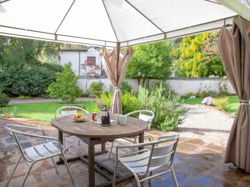 a table and chairs under an umbrella in a garden at Little Millhayes in Thorverton