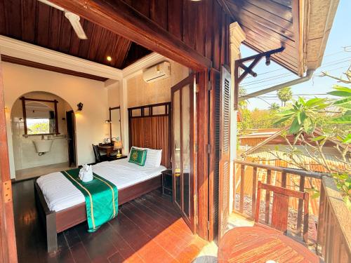 a bedroom with a bed and a balcony at Villa Xiengthong Garden View Hotel in Luang Prabang
