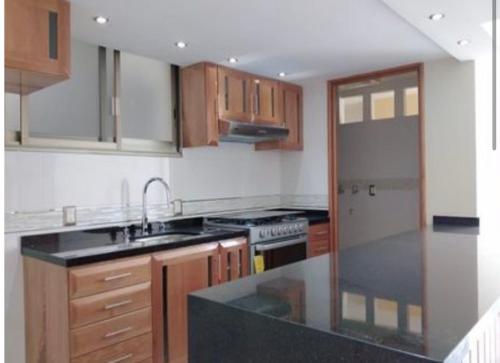 a kitchen with wooden cabinets and a black counter top at Suites en la zona más cool in Guadalajara