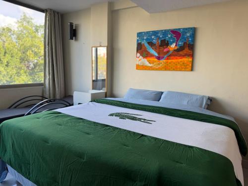 a bedroom with a bed with a green blanket at Suites en la zona más cool in Guadalajara