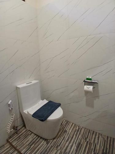 a bathroom with a toilet with a blue towel on it at Mini Village in Batukaras