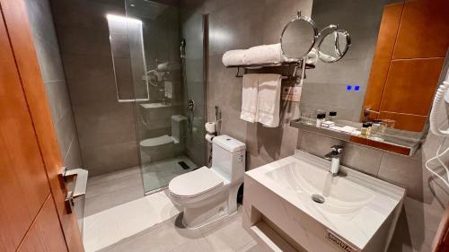 a bathroom with a toilet and a sink and a mirror at W Suites Hotel Sama Abha in Abha