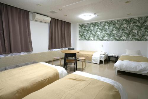 a hotel room with two beds and a table at HOTEL Reise Basis ホテルライゼベイシス Kakunodate in Akita in Senboku