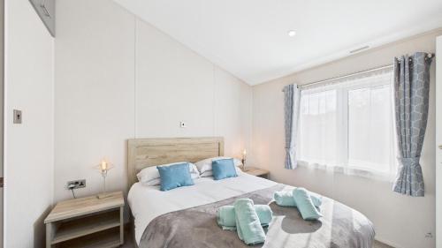 a bedroom with a large white bed with blue pillows at Rowan a welcoming countryside lodge in Ryde