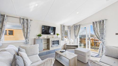 a living room with a couch and chairs and a tv at Rowan a welcoming countryside lodge in Ryde