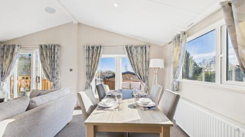 a dining room with a table and chairs and windows at Rowan a welcoming countryside lodge in Ryde