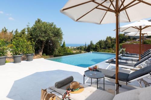 a villa with a swimming pool and an umbrella at Cicada Villa in Koskinou