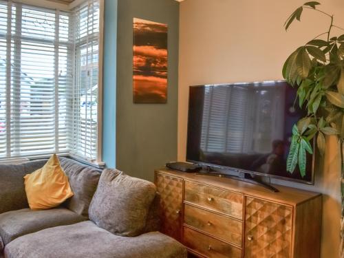 a living room with a couch and a flat screen tv at Nala's Cottage in Skegness