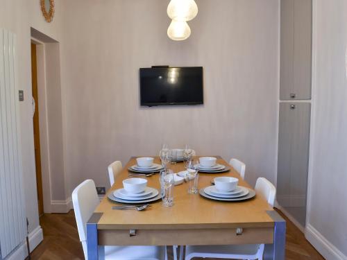 a wooden table with white chairs and a television on a wall at Nala's Cottage in Skegness