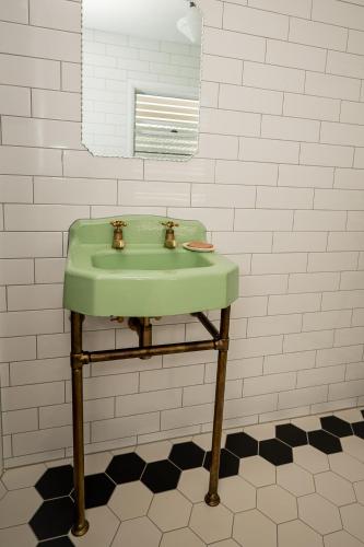 a green sink in a bathroom with a mirror at Herbgully Cottage in Roma