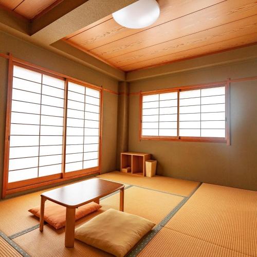 a living room with a table and three windows at 春日旅館-Kasuga Ryokan- in Nabari