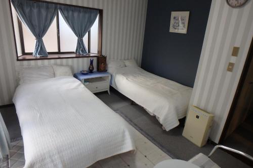 two beds in a room with a window at KazenoKi in Kichijōji